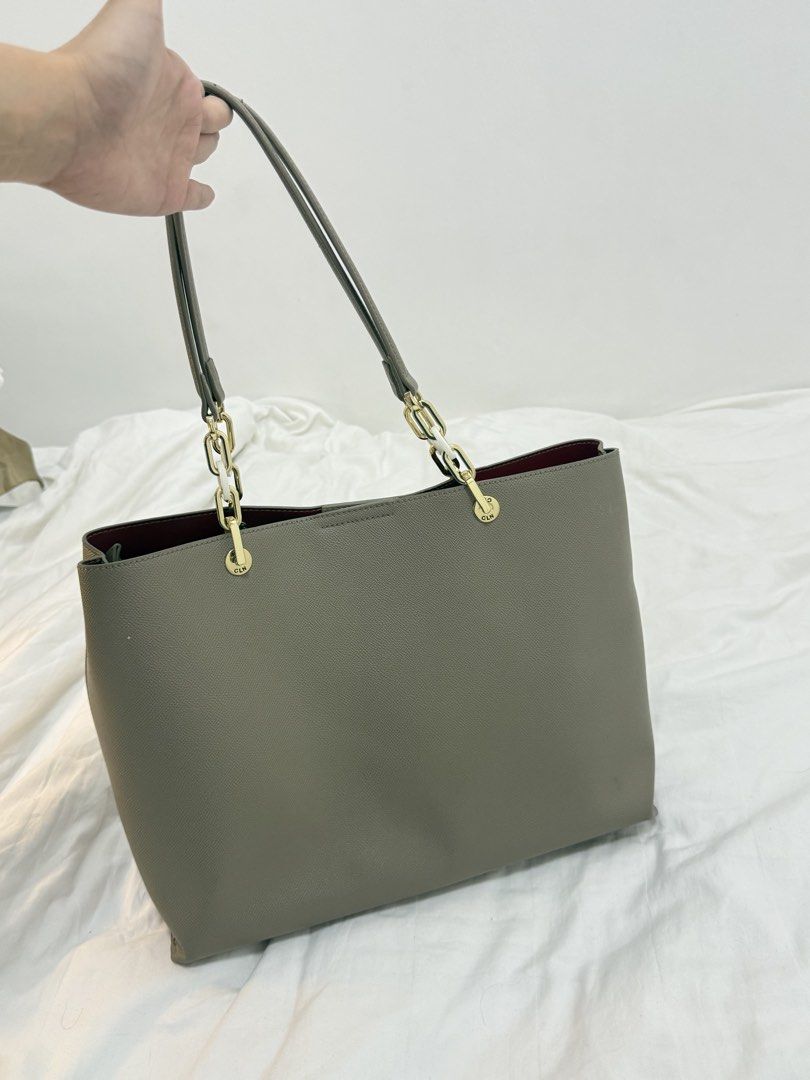 CLN Grey Tote Bag with Gold Hardware (Category: Tote Bags) located in Manila. Submitted by k.e9999 (Listing ID 1471263325, Image 2). Description: - Brand: CLN - Material: Grey faux leather with a structured design - Interior: Vibrant red silky fabric lining with patterned compartments - Organization: Multiple zippered sections to keep your essentials secure - Details: Elegant gold chain links on the shoulder straps and a matching front charm - Ca