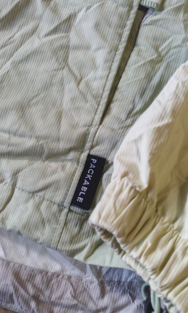 Columbia Packable Windbreaker Hooded Jacket Green (Category: Coats, Jackets and Outerwear) located in Indang. Submitted by shanlennon09 (Listing ID 1471131532, Image 2). Description: - Brand: Columbia - Color: Pastel green and cream - Design: Packable hooded windbreaker with full zip closure - Features: Adjustable drawstrings on the hood, elastic cuffs, and Columbia logo patch near the hem - Material: Lightweight nylon - Best for: Outdoor activit