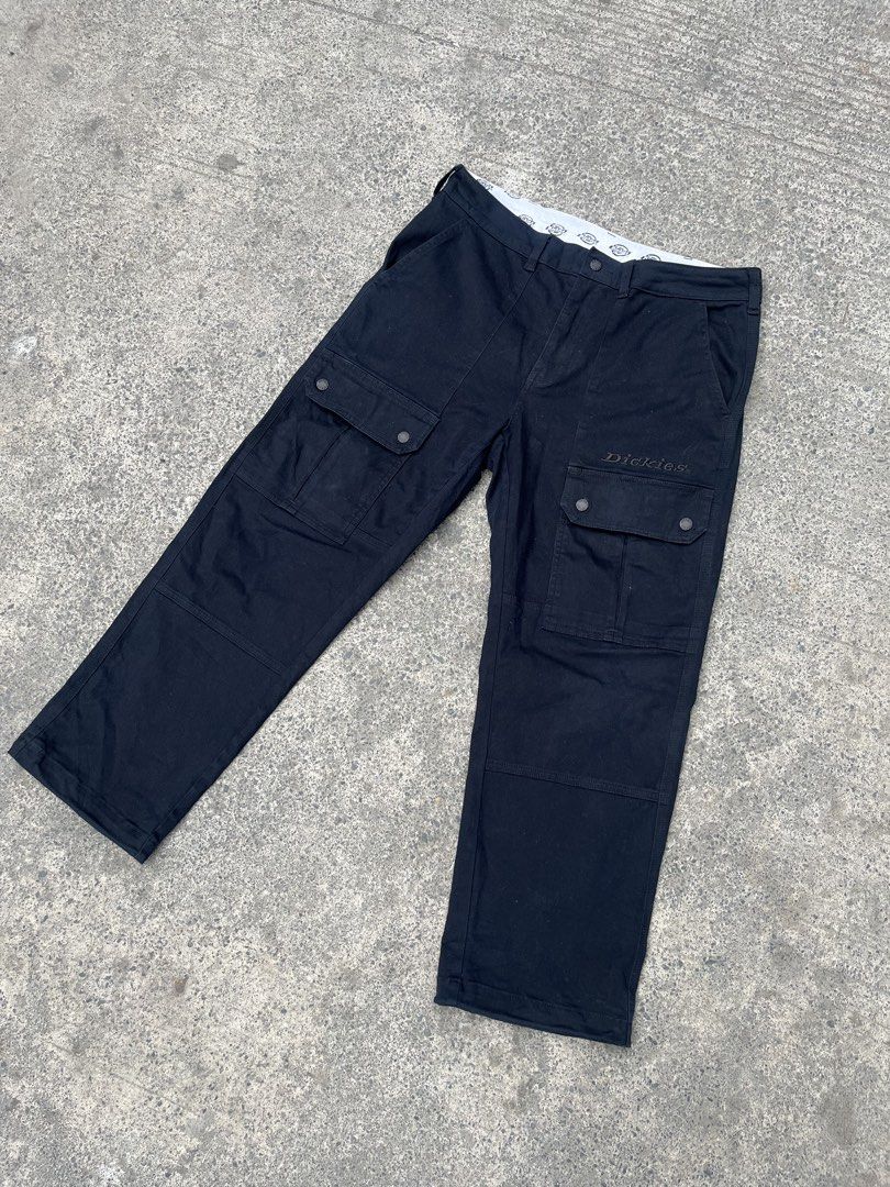 Dickies 1922 Black Cargo Pants (Category: Trousers) located in Manila. Submitted by donthriftph. (Listing ID 1471196945, Image 1). Description: - Brand: Dickies 1922 - Color: Solid black - Fit: Straight fit through the legs - Material: Heavy-duty, durable fabric - Pockets: Multiple utility pockets with snap button flaps - Details: Branded inner waistband with logo print, embroidered logo on left cargo pocket, button fly, and branded metal buttons