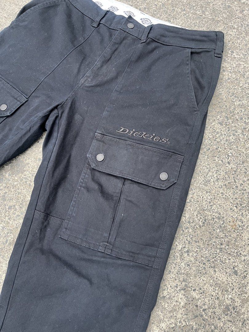 Dickies 1922 Black Cargo Pants (Category: Trousers) located in Manila. Submitted by donthriftph. (Listing ID 1471196945, Image 3). Description: - Brand: Dickies 1922 - Color: Solid black - Fit: Straight fit through the legs - Material: Heavy-duty, durable fabric - Pockets: Multiple utility pockets with snap button flaps - Details: Branded inner waistband with logo print, embroidered logo on left cargo pocket, button fly, and branded metal buttons