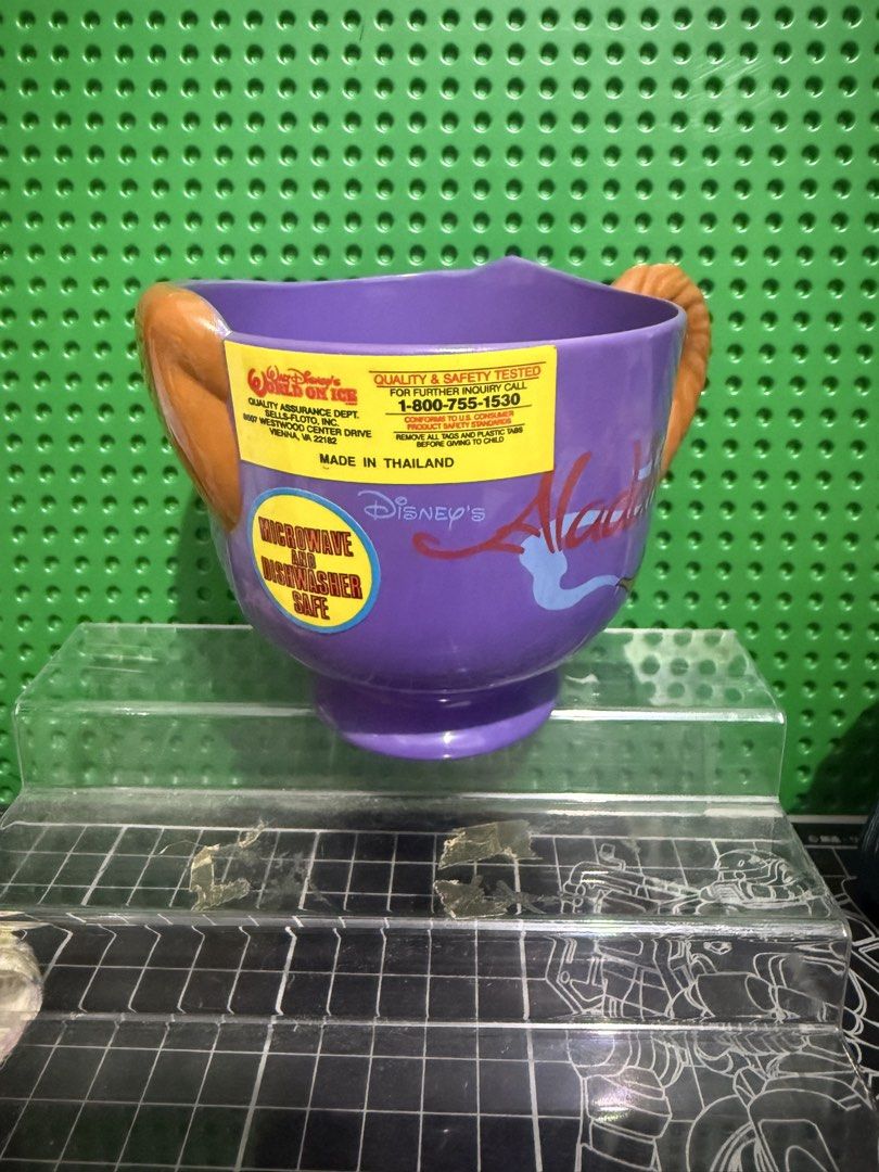 Disney Aladdin Abu Character Purple Mug (Category: Coffee & Tea Tableware) located in Victoria. Submitted by pisangpaulotoys (Listing ID 1471289055, Image 3). Description: - Disney Aladdin Abu character mug in purple - Molded Abu face on the front with his tail as the handle - Microwave and dishwasher safe - Manufactured in Thailand for Walt Disney's World on Ice - Original safety and quality testing sticker still attached - Perfect collectible f