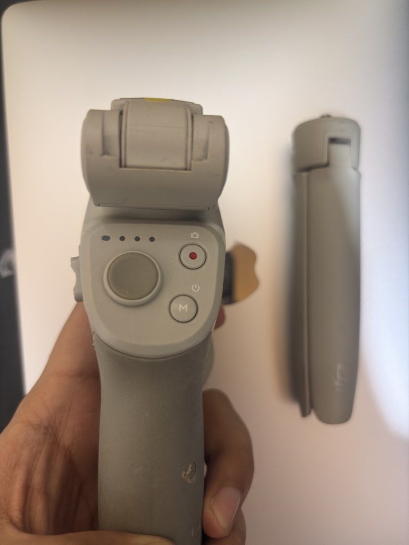 DJI Osmo Mobile 4 Gimbal Stabilizer (Category: Gimbals & Stabilizers ) located in Taguig. Submitted by adrian_85 (Listing ID 1471270081, Image 1). Description: - Model: DJI Osmo Mobile 4 smartphone gimbal stabilizer - Condition: Fully functional, with visible wear and scuffs from regular use - Included: Magnetic phone clamp, mini tripod stand, and attached wrist strap - Features: Excellent for stable video recording, live streaming, and on-the-go