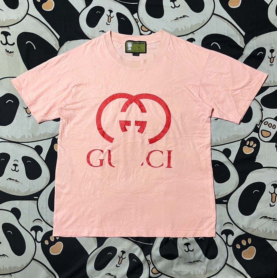 Doraemon x Gucci Pink T-shirt (Category: Shirts) located in Taguig. Submitted by 22nd_street_thrift (Listing ID 1471164722, Image 1). Description: Collaboration tee from Doraemon and Gucci. Pink cotton fabric with large red intertwined G logo printed on the chest. Special green collar tag featuring Doraemon artwork and Fujiko Pro copyright text. Made in Italy label attached below the neck tag. Long interior care label included..