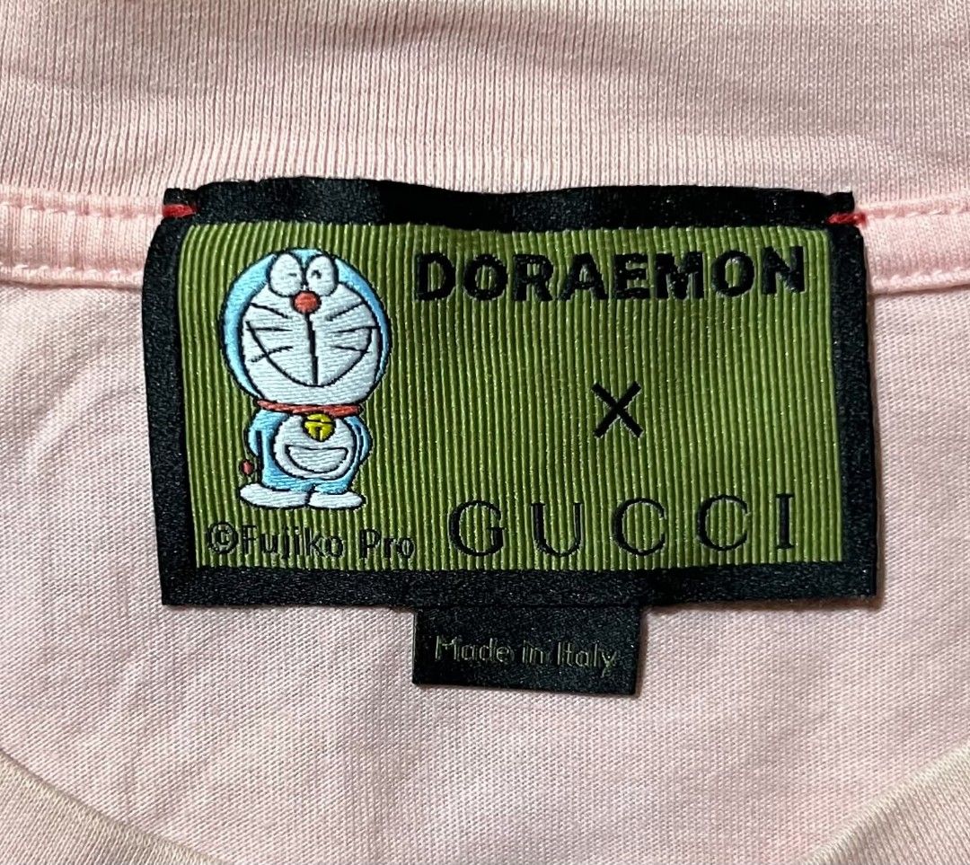 Doraemon x Gucci Pink T-shirt (Category: Shirts) located in Taguig. Submitted by 22nd_street_thrift (Listing ID 1471164722, Image 3). Description: Collaboration tee from Doraemon and Gucci. Pink cotton fabric with large red intertwined G logo printed on the chest. Special green collar tag featuring Doraemon artwork and Fujiko Pro copyright text. Made in Italy label attached below the neck tag. Long interior care label included..