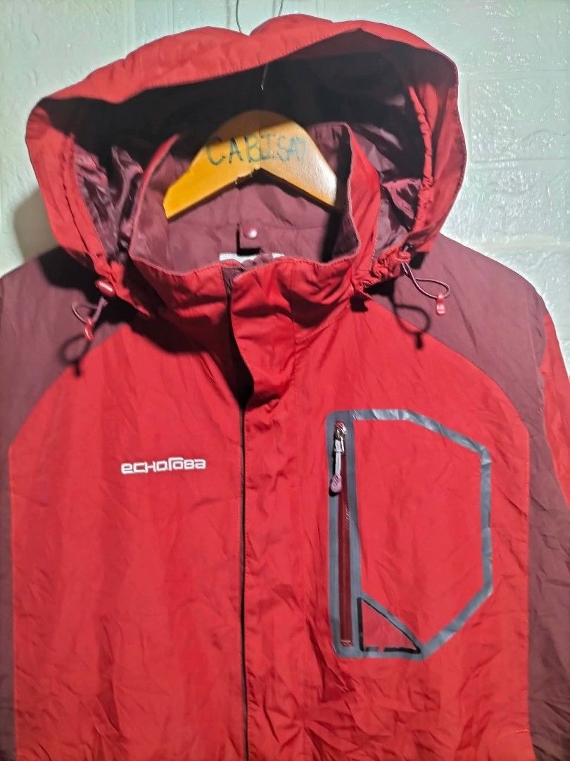 Echorova Red Hooded Outdoor Jacket (Category: Coats, Jackets and Outerwear) located in Valencia. Submitted by cabisaythriftshop (Listing ID 1471225717, Image 2). Description: - Brand: Echorova - Color: Red and maroon - Hood with adjustable drawstrings - Front zip closure with Velcro storm flap - Functional chest pocket with zip detailing - Adjustable Velcro cuffs for a better fit - Authentic brand label stitched inside the collar.
