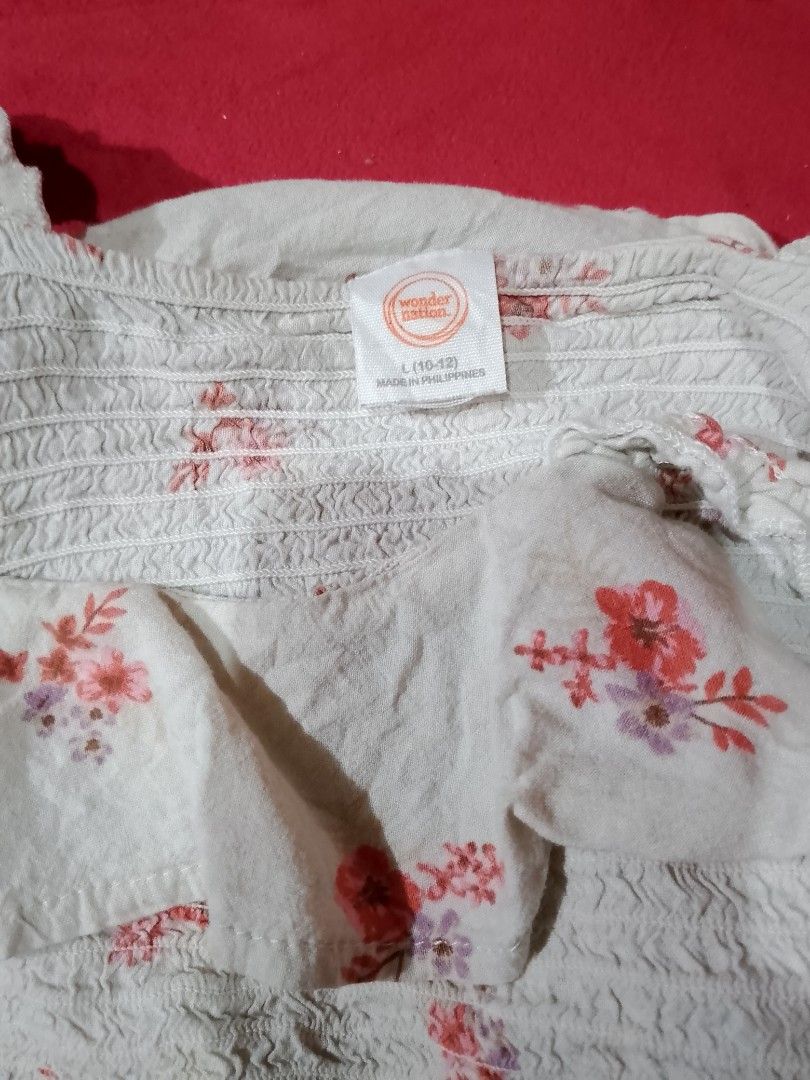 Floral Smocked Crop Top (Category: Blouses) located in Batangas. Submitted by sheenx.09 (Listing ID 1471253288, Image 2). Description: - Brand: Wonder Nation - Size: L (Kids 10-12) xs to s only - Color: White with pink floral print 😍 - Design: Square neckline, ruffle trim, textured straps, and stretchy smocked bodice 💛 - Condition: Brand new / Excellent - Perfect for: Summer outfits, easy to pair with high-waisted jeans or skirts 😃 - Made in t