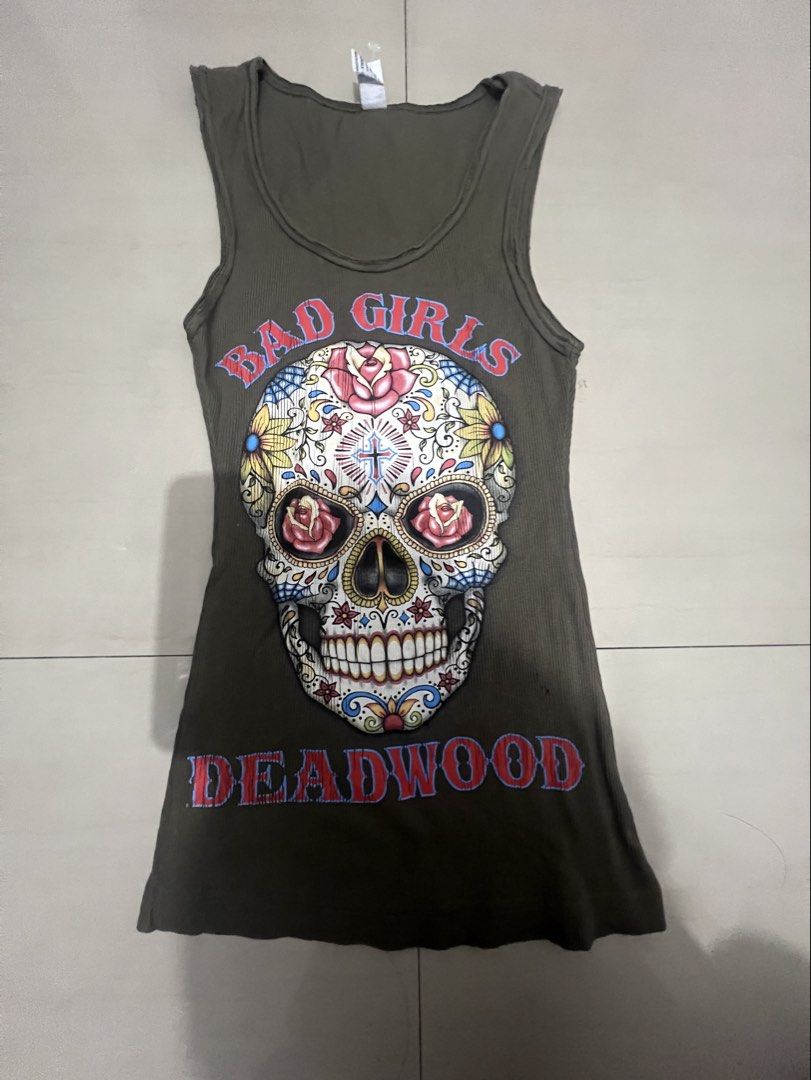Form Fitting Dark Green Skull Ribbed Graphic Tank Top (Category: Sleeveless) located in Caloocan City. Submitted by guaconerva97479 (Listing ID 1471119709, Image 1). Description: - Color: Olive green - Style: Fitted ribbed tank top with scoop neckline and sleeveless design - Graphic: Large sugar skull with floral roses, spiderweb details, and 'BAD GIRLS DEADWOOD' lettering - Material: Soft stretch fabric for a comfortable fit - Condition: Brand n