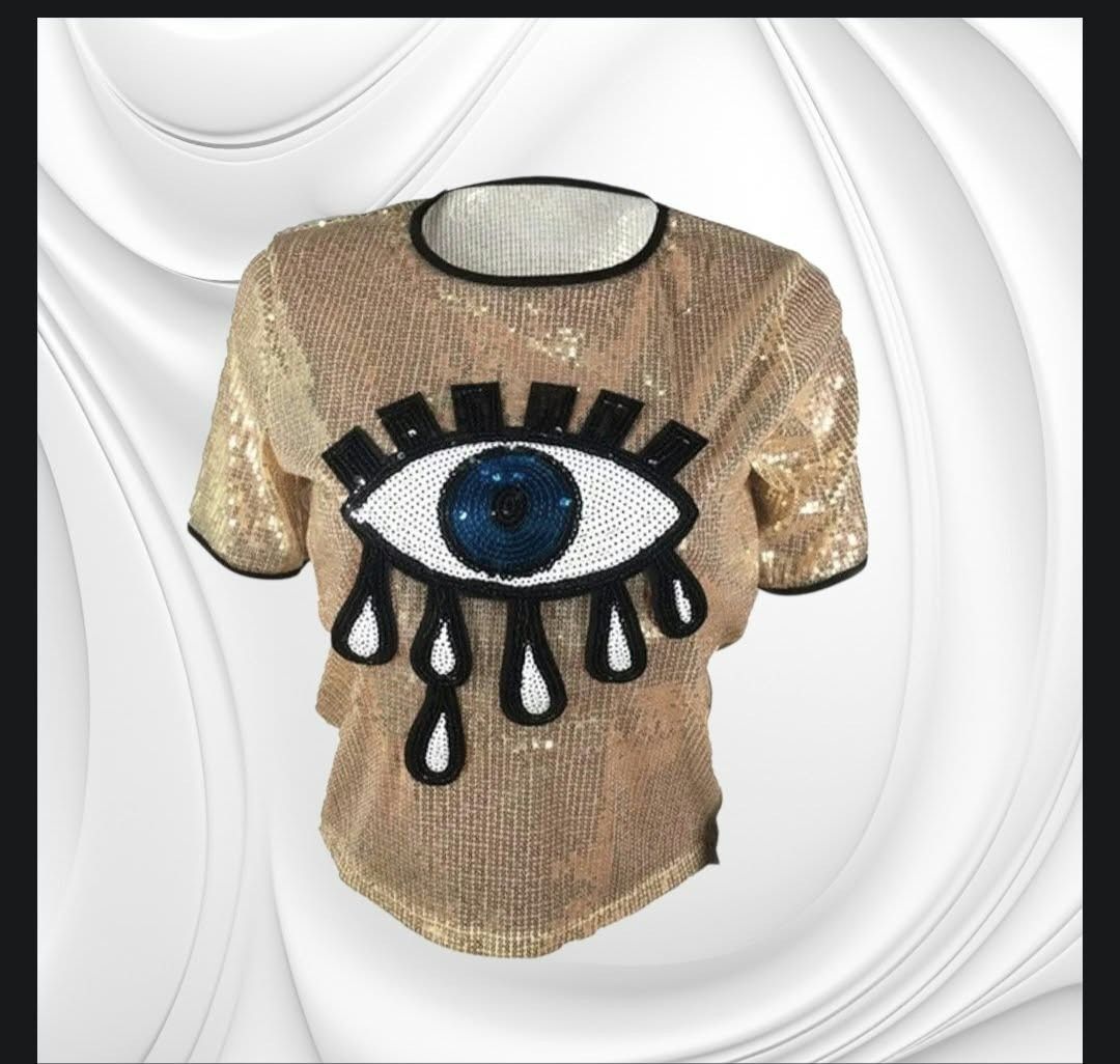 Gold Sequin T-Shirt with Evil Eye Graphic (Category: Shirts) located in Paranaque City. Submitted by calm_youngstore7 (Listing ID 1471245159, Image 3). Description: - Stunning gold sequin short-sleeve top - Features a large beaded evil eye design with black & white details and dangling teardrops - Plain gold sequins on the back - Stylish black trim on the crew neck and sleeves - Fully covered in shiny, eye-catching sequins - Condition: Brand new 