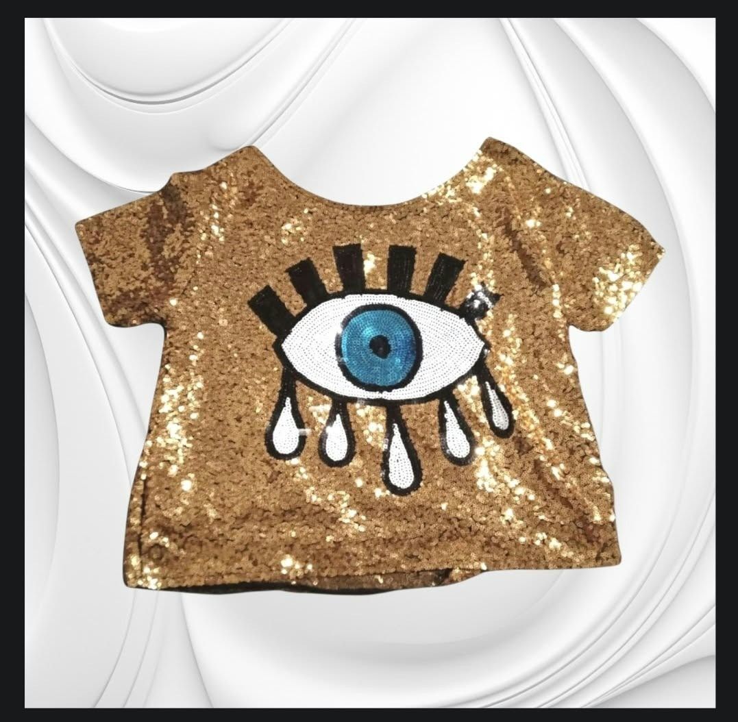Gold Sequin T-Shirt with Evil Eye Graphic (Category: Shirts) located in Paranaque City. Submitted by calm_youngstore7 (Listing ID 1471245159, Image 1). Description: - Stunning gold sequin short-sleeve top - Features a large beaded evil eye design with black & white details and dangling teardrops - Plain gold sequins on the back - Stylish black trim on the crew neck and sleeves - Fully covered in shiny, eye-catching sequins - Condition: Brand new 