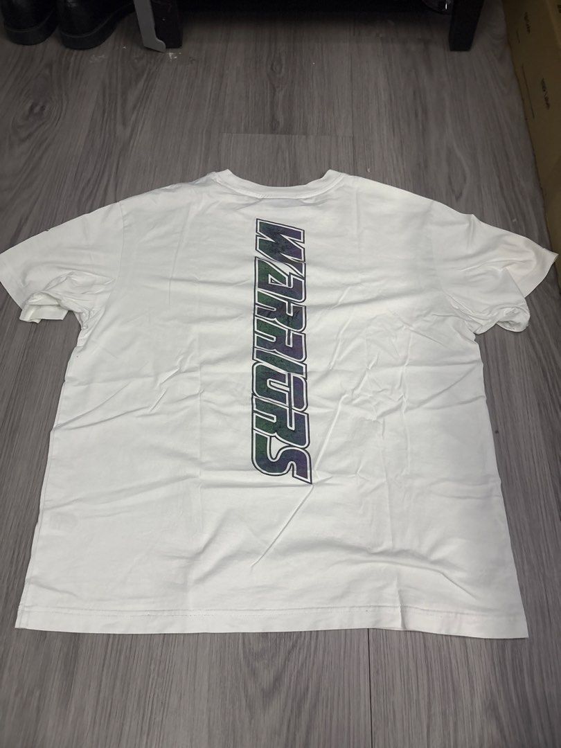 Golden State Warriors NBA White Graphic T-Shirt (Category: Tshirts & Polo Shirts ) located in Binan City. Submitted by rre1yes (Listing ID 1471237147, Image 2). Description: - Authentic Golden State Warriors white t-shirt - Front features GSW text logo and official NBA collar tag - Sleeve is accented with a team patch - Back showcases a large, colorful vertical Warriors graphic - Designed with a comfortable ribbed crew neck - Perfect for fans and