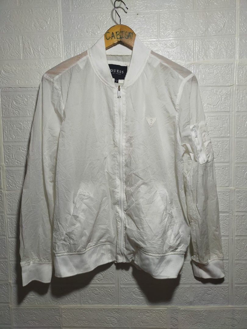 Guess Los Angeles White Bomber Jacket Size M (Category: Coats, Jackets and Outerwear) located in Valencia. Submitted by cabisaythriftshop (Listing ID 1471221935, Image 1). Description: - Brand: Guess Los Angeles - Item: Nylon Bomber Jacket - Color: White - Size: Medium - Features: Zip-up front, matching white zipper pulls, ribbed cuffs/collar/hem, triangular logo patch on chest, utility zipper pocket on left sleeve - Material: Lightweight, ideal 