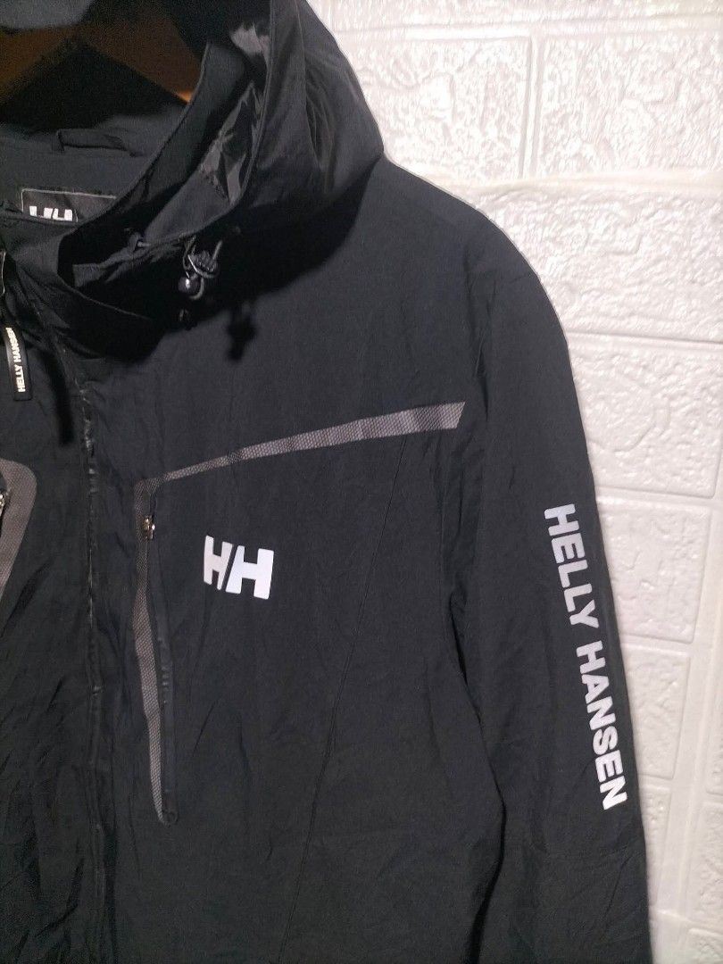 Helly Hansen Black H2Flow Waterproof Hooded Jacket Size 100 (Category: Coats, Jackets and Outerwear) located in Valencia. Submitted by cabisaythriftshop (Listing ID 1471225775, Image 3). Description: - Brand: Helly Hansen - Color: Black with olive green and black polka dot mesh lining - Size: 100 slim fit - Technology: Helly Tech Protection with H2Flow system for breathability and warmth regulation - Pockets: Waterproof chest pockets and a dedica