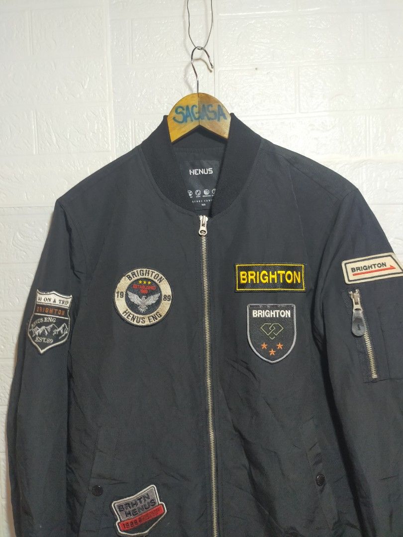 Henus Brighton Bomber Jacket Black Patches (Category: Coats, Jackets and Outerwear) located in Valencia. Submitted by cabisaythriftshop (Listing ID 1471223489, Image 2). Description: - Brand: Henus Brighton - Color: Black - Style: Bomber jacket (Standard fit) - Closure: Full zip front - Details: Multiple patches on chest and sleeves - Pockets: Zipper utility pocket on left arm - Features: Ribbed cuffs and hem - Condition: Clean look, solid zipper