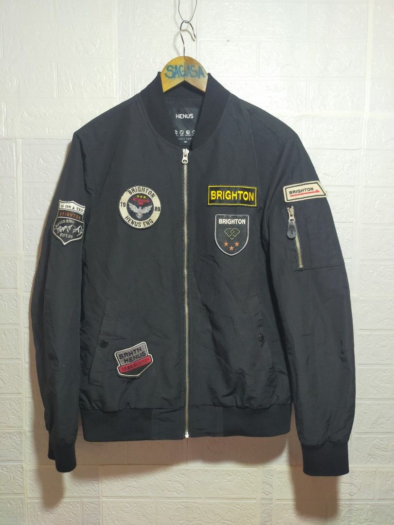 Henus Brighton Bomber Jacket Black Patches (Category: Coats, Jackets and Outerwear) located in Valencia. Submitted by cabisaythriftshop (Listing ID 1471223489, Image 1). Description: - Brand: Henus Brighton - Color: Black - Style: Bomber jacket (Standard fit) - Closure: Full zip front - Details: Multiple patches on chest and sleeves - Pockets: Zipper utility pocket on left arm - Features: Ribbed cuffs and hem - Condition: Clean look, solid zipper