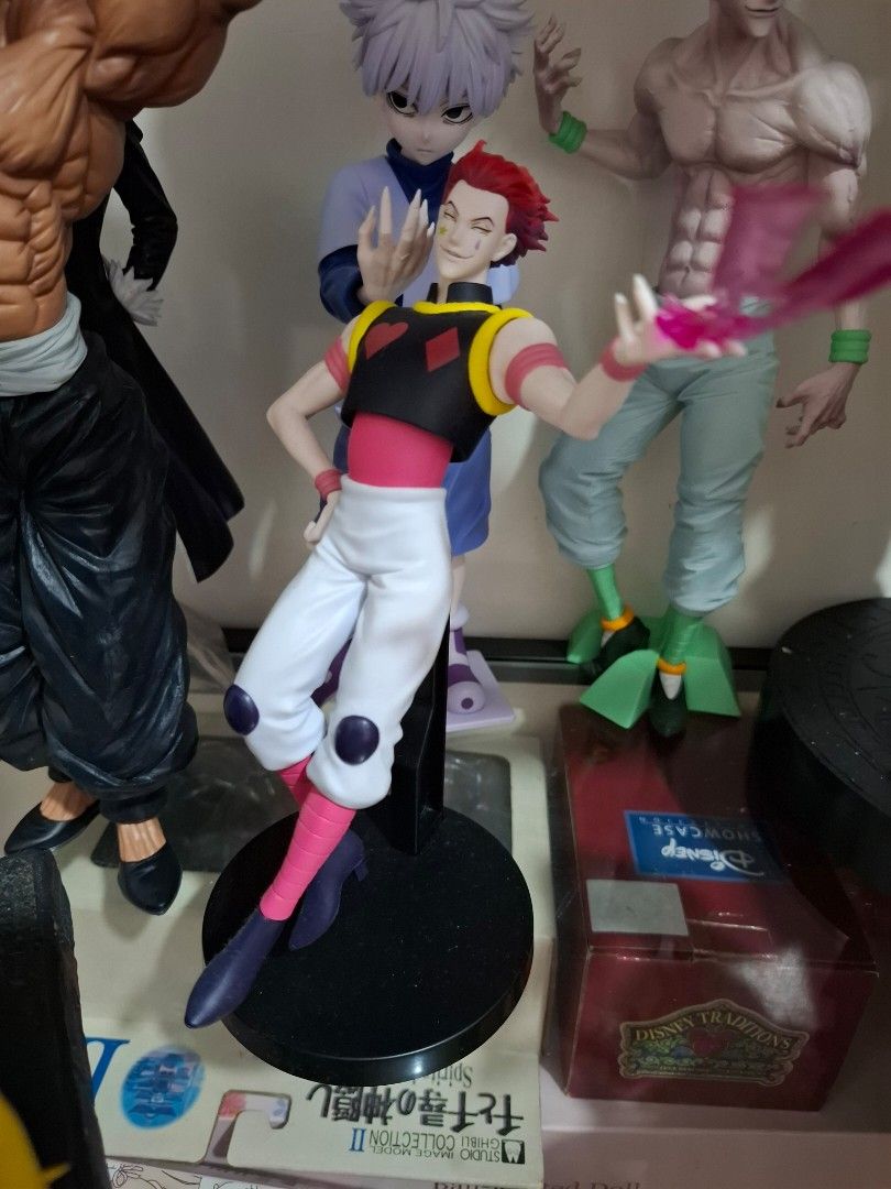 Hunter x Hunter Hisoka Action Figure (Category: Figurines & Statues) located in Orion. Submitted by timburtonfan (Listing ID 1471125365, Image 1). Description: - Character: Hisoka from Hunter x Hunter - Design: Dynamic pose featuring his iconic red hair, face markings, and purple/yellow outfit - Special Feature: Includes a translucent pink aura effect piece on one hand - Base: Comes with a sturdy black circular stand and support rod - Condition: 