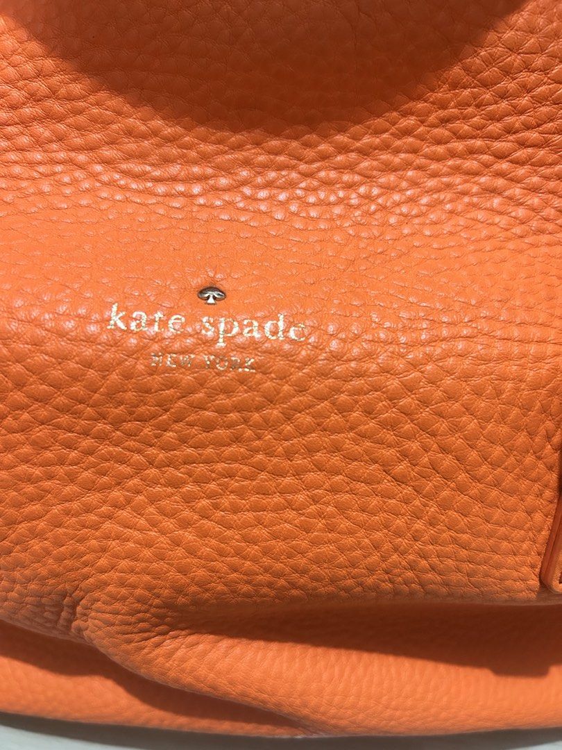 Kate Spade Orange Leather Satchel Bag (Category: Luxury Bags & Wallets) located in Manila. Submitted by ai010 (Listing ID 1471211182, Image 3). Description: - Brand: Kate Spade New York - Material: Vibrant orange pebble leather with silver-tone hardware - Closure: Secure zip-top closure - Carrying Options: Dual top handles and a detachable, adjustable crossbody strap - Interior: Clean cream fabric lining with signature text pattern, 1 zip pocket,
