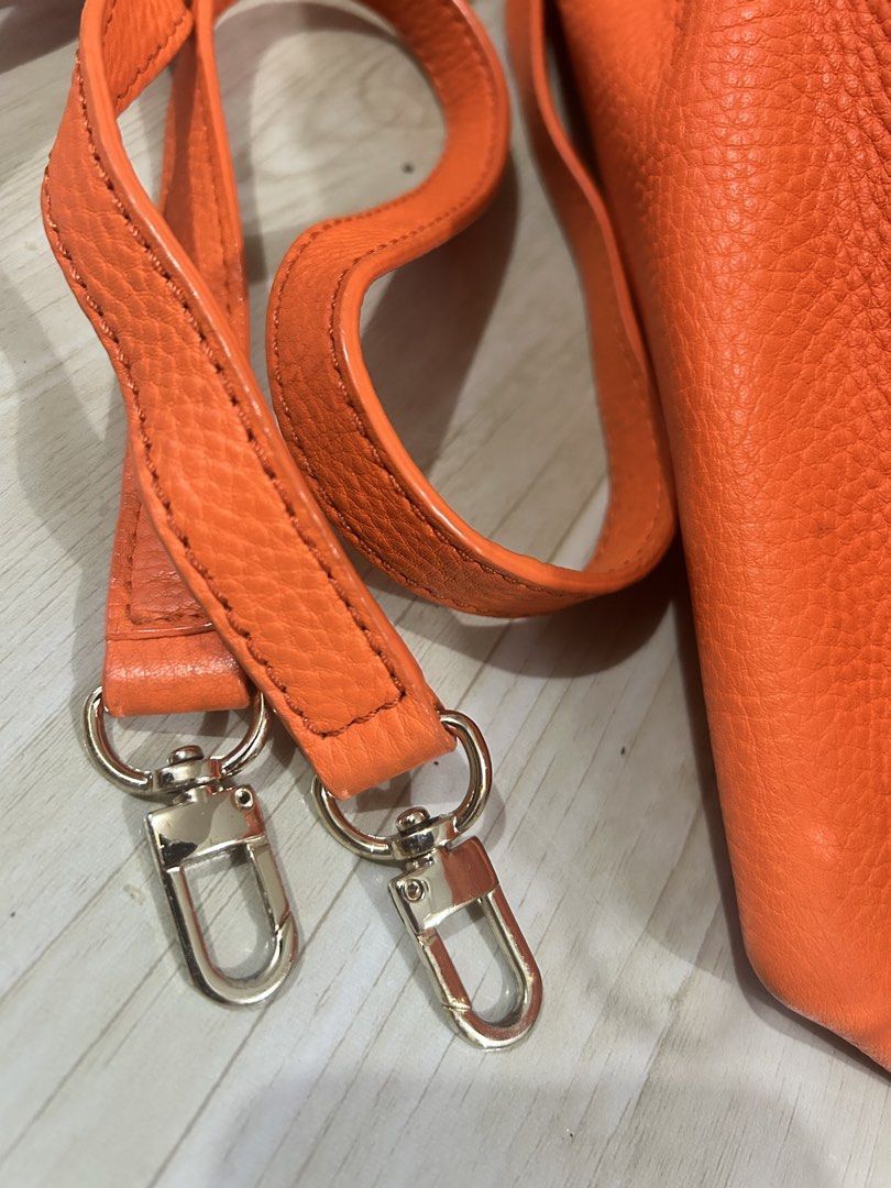 Kate Spade Orange Leather Satchel Bag (Category: Luxury Bags & Wallets) located in Manila. Submitted by ai010 (Listing ID 1471211182, Image 2). Description: - Brand: Kate Spade New York - Material: Vibrant orange pebble leather with silver-tone hardware - Closure: Secure zip-top closure - Carrying Options: Dual top handles and a detachable, adjustable crossbody strap - Interior: Clean cream fabric lining with signature text pattern, 1 zip pocket,