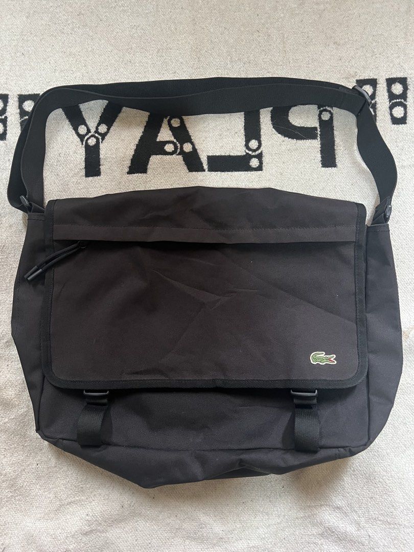 Lacoste Black Messenger Bag Crossbody (Category: Sling Bags) located in Cagayan de Oro. Submitted by nelsondel21723 (Listing ID 1471168287, Image 1). Description: Black Lacoste messenger bag. Durable canvas material with adjustable shoulder strap. Flap closure featuring dual plastic buckles and embroidered green crocodile logo in the corner. Zip pocket on the front flap with pull cords. Spacious interior compartment with fabric lining. Great ever