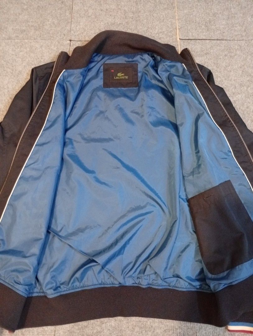 Lacoste Bomber Jacket Size 50 Blue Black (Category: Coats, Jackets and Outerwear) located in Cebu City. Submitted by jeanyrose46 (Listing ID 1471281779, Image 2). Description: - Brand: Lacoste - Style: Bomber Jacket - Color: Dark blue and black with vibrant blue inner lining - Details: Navy, white, and red striped ribbed collar, cuffs, and hem - Pockets: Full zip closure, zipped side pockets, and one interior pocket - Size: 50 (Best for 100cm che