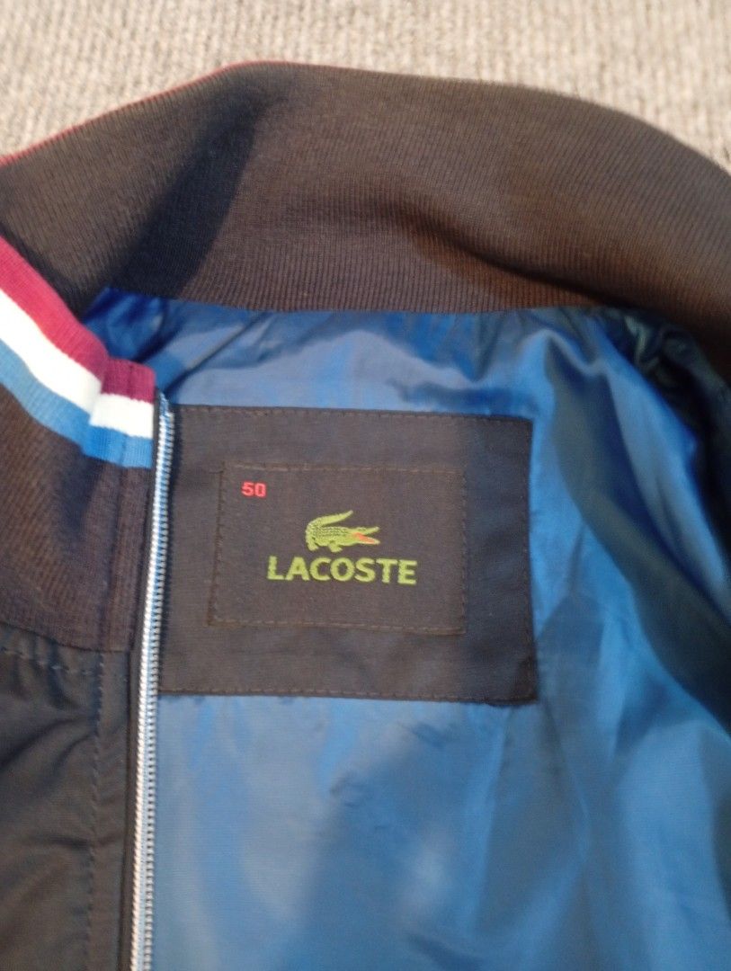 Lacoste Bomber Jacket Size 50 Blue Black (Category: Coats, Jackets and Outerwear) located in Cebu City. Submitted by jeanyrose46 (Listing ID 1471281779, Image 3). Description: - Brand: Lacoste - Style: Bomber Jacket - Color: Dark blue and black with vibrant blue inner lining - Details: Navy, white, and red striped ribbed collar, cuffs, and hem - Pockets: Full zip closure, zipped side pockets, and one interior pocket - Size: 50 (Best for 100cm che