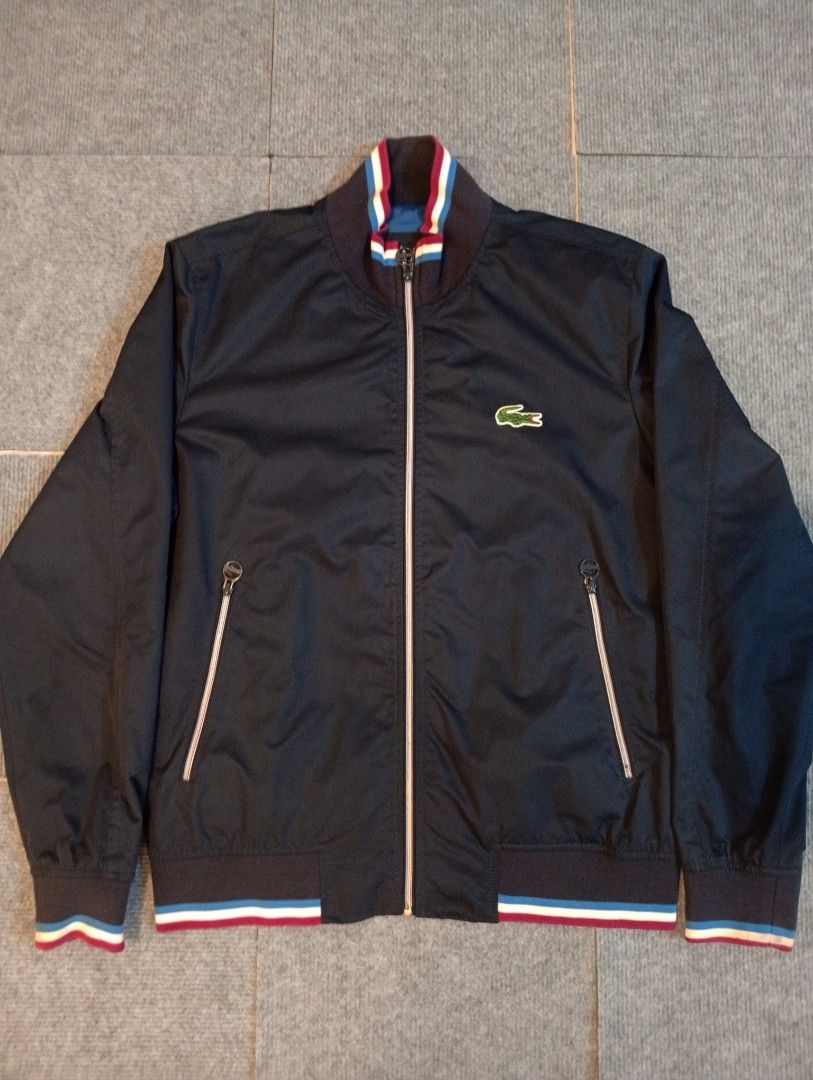 Lacoste Bomber Jacket Size 50 Blue Black (Category: Coats, Jackets and Outerwear) located in Cebu City. Submitted by jeanyrose46 (Listing ID 1471281779, Image 1). Description: - Brand: Lacoste - Style: Bomber Jacket - Color: Dark blue and black with vibrant blue inner lining - Details: Navy, white, and red striped ribbed collar, cuffs, and hem - Pockets: Full zip closure, zipped side pockets, and one interior pocket - Size: 50 (Best for 100cm che