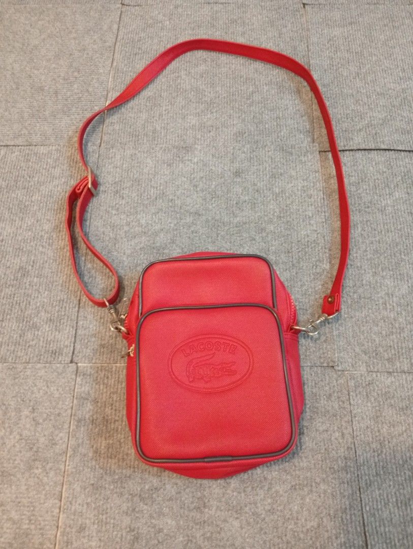 Lacoste Red Crossbody Bag with Adjustable Strap (Category: Cross-body Bags) located in Cebu City. Submitted by jeanyrose46 (Listing ID 1471281864, Image 1). Description: - Brand: Lacoste - Color: Bright Red - Style: Structured crossbody bag with adjustable shoulder strap and metal hardware - Exterior: Front zipped pocket with debossed crocodile logo patch - Interior: Lined in black fabric with internal brand tag - Size: Compact, ideal for daily e