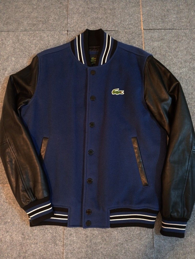 Lacoste Varsity Bomber Jacket Blue Black Size 48 (Category: Coats, Jackets and Outerwear) located in Cebu City. Submitted by jeanyrose46 (Listing ID 1471281647, Image 1). Description: - Classic varsity jacket style with blue wool body and black leather sleeves - Size 48 (labeled on inner brand tag) - Warm quilted black inner lining - Snap-button front closure with two functional welt pockets - Ribbed collar and cuffs featuring white striping - Cl