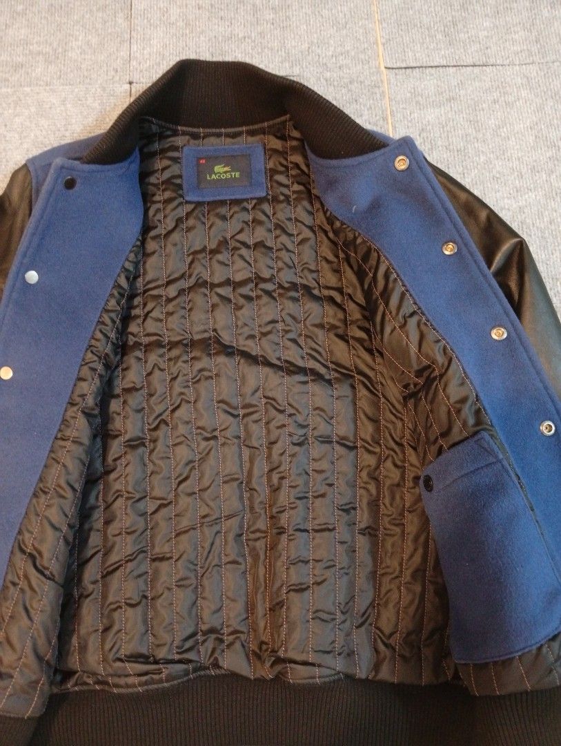 Lacoste Varsity Bomber Jacket Blue Black Size 48 (Category: Coats, Jackets and Outerwear) located in Cebu City. Submitted by jeanyrose46 (Listing ID 1471281647, Image 3). Description: - Classic varsity jacket style with blue wool body and black leather sleeves - Size 48 (labeled on inner brand tag) - Warm quilted black inner lining - Snap-button front closure with two functional welt pockets - Ribbed collar and cuffs featuring white striping - Cl