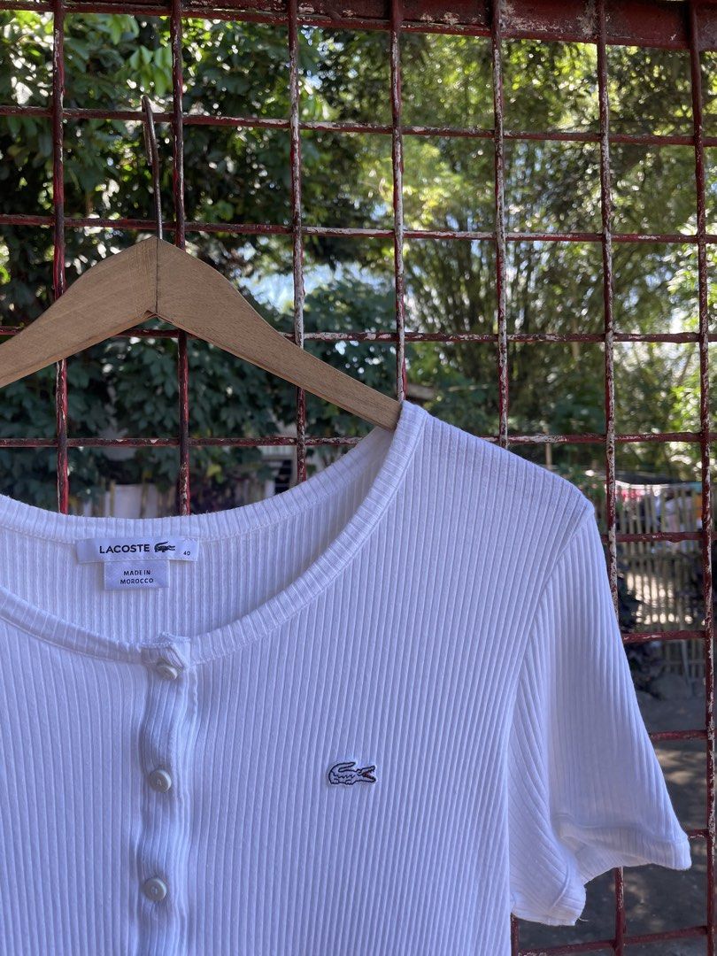Lacoste White Ribbed Button-Down Short Sleeve Top Size 40 (Category: Shirts) located in Polomolok. Submitted by madagascarts (Listing ID 1471120631, Image 3). Description: - Brand: Lacoste - Color: Clean White - Size: 40 (Tag attached) - Material: Soft Cotton and Modal blend - Origin: Made in Morocco - Design: Ribbed texture, short sleeves, scoop neckline, and partial front button placket - Detail: Iconic embroidered crocodile logo on the left ch