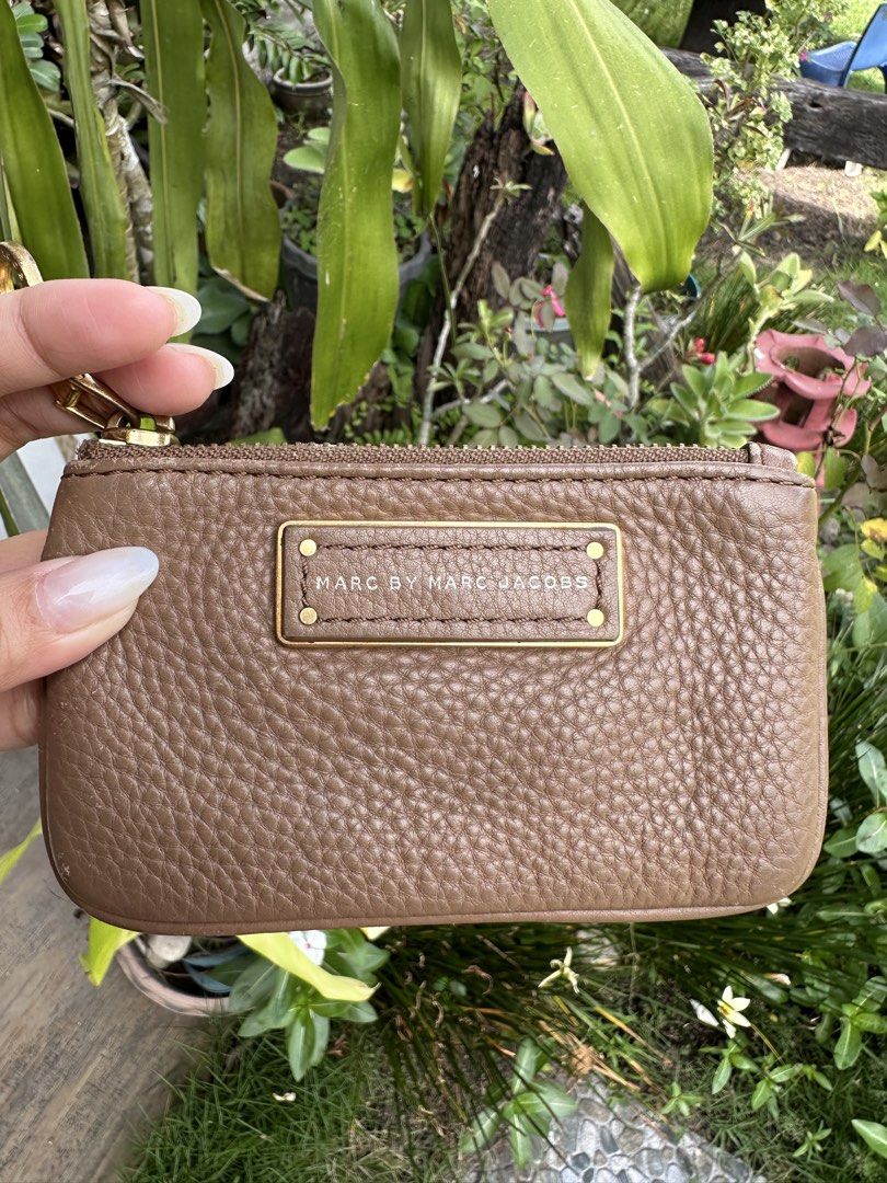 Marc by Marc Jacobs Brown Leather Zip Pouch (Category: Luxury Bags & Wallets) located in Bombon. Submitted by cookiespreloveed (Listing ID 1471161847, Image 1). Description: - Brand: Marc by Marc Jacobs - Material: Brown pebble leather - Hardware: Gold metal logo plaque and engraved round zipper pull - Function: Compact pouch ideal for storing cards, coins, and small essentials - Condition: Normal signs of wear along the bottom edges.