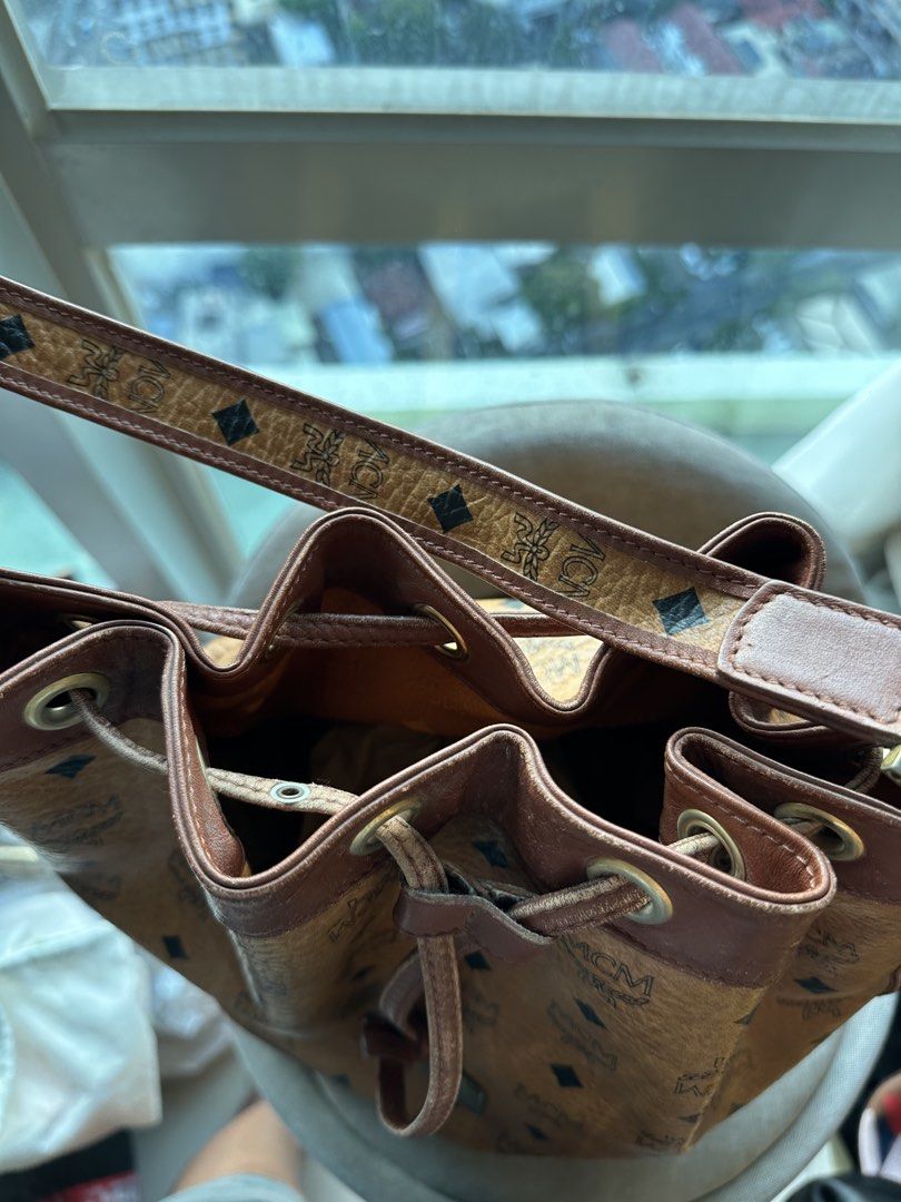 MCM Visetos Monogram Leather Bucket Bag (Category: Luxury Bags & Wallets) located in Imus. Submitted by ann__xoxo (Listing ID 1471165439, Image 2). Description: - Authentic MCM bucket bag in classic brown monogram coated canvas - Dark brown leather trim and gold-tone hardware - Secure drawstring closure with an adjustable shoulder strap - MCM monogram fabric interior lining with a convenient zippered pocket - Features the iconic serial number pla