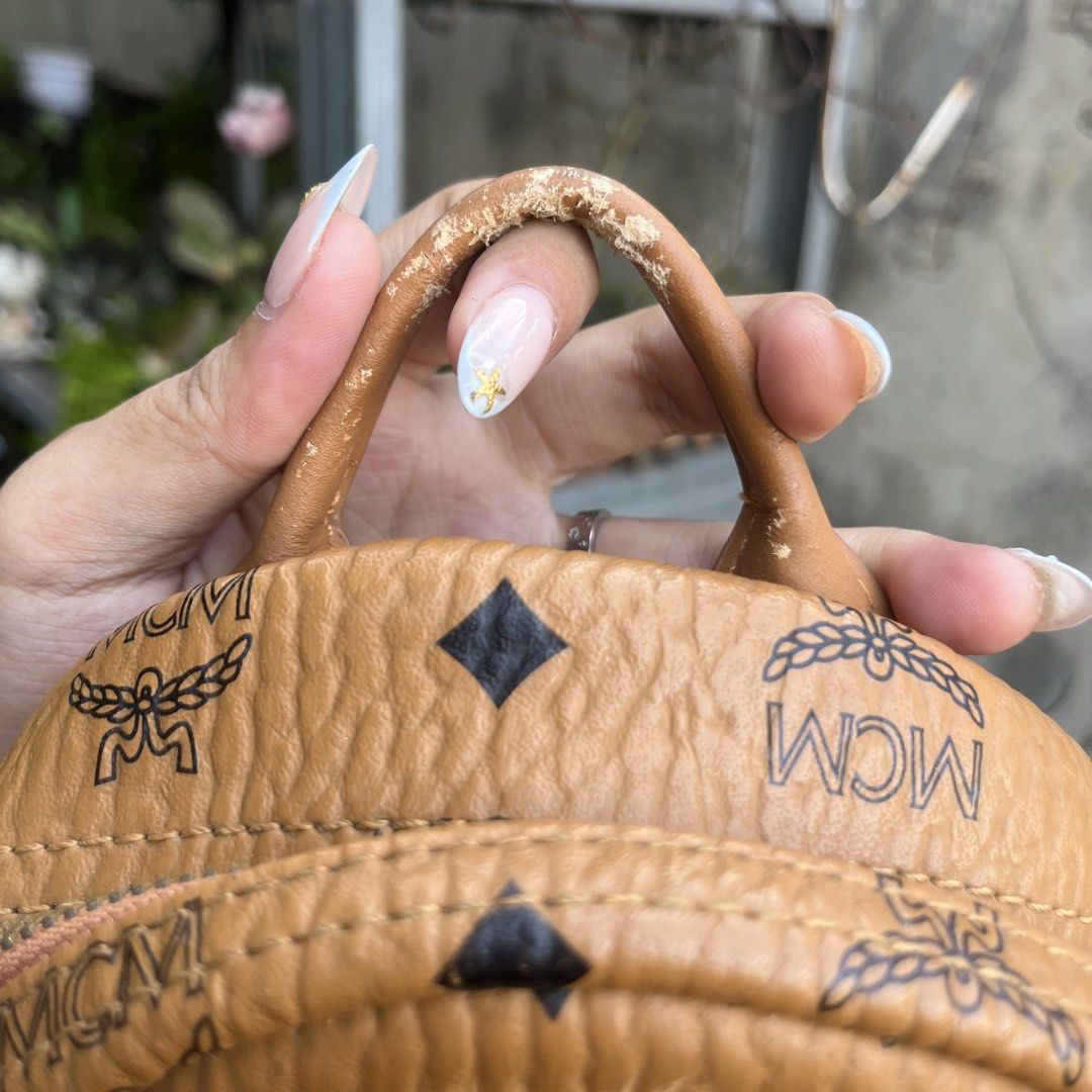 MCM Visetos Monogram Studded Mini Backpack Cognac (Category: Luxury Bags & Wallets) located in Davao. Submitted by ange030405 (Listing ID 1471165862, Image 3). Description: Cognac Visetos monogram coated canvas mini backpack by MCM. Iconic all-over print with black diamonds and laurel motif. Gold-tone hardware, metal logo plaque reading 1113L, and pyramid studs on both side pockets. Front zippered compartment, top handle, and adjustable convertib