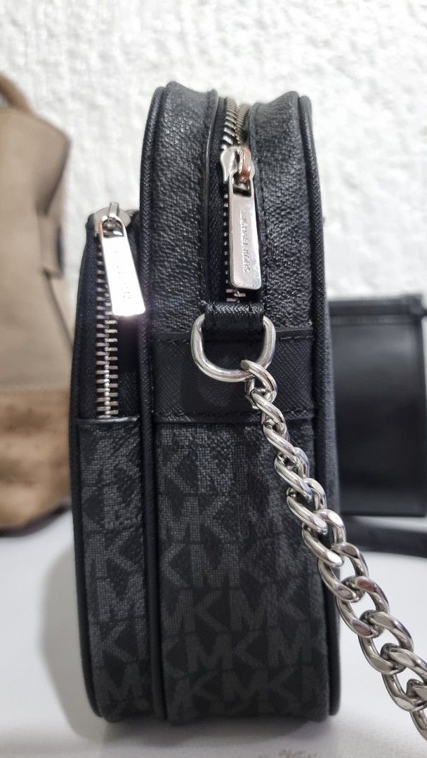 Michael Kors MK Monogram Black Crossbody Bag (Category: Luxury Bags & Wallets) located in Quezon City. Submitted by finds.in.closet (Listing ID 1471221835, Image 2). Description: - Brand: Michael Kors - Color: Black with signature MK monogram print - Compartments: Double zip top compartments plus an extra front pocket - Interior: Fabric lining with MK branding, very clean condition - Hardware: Silver-tone with chic chain strap detail on the side 