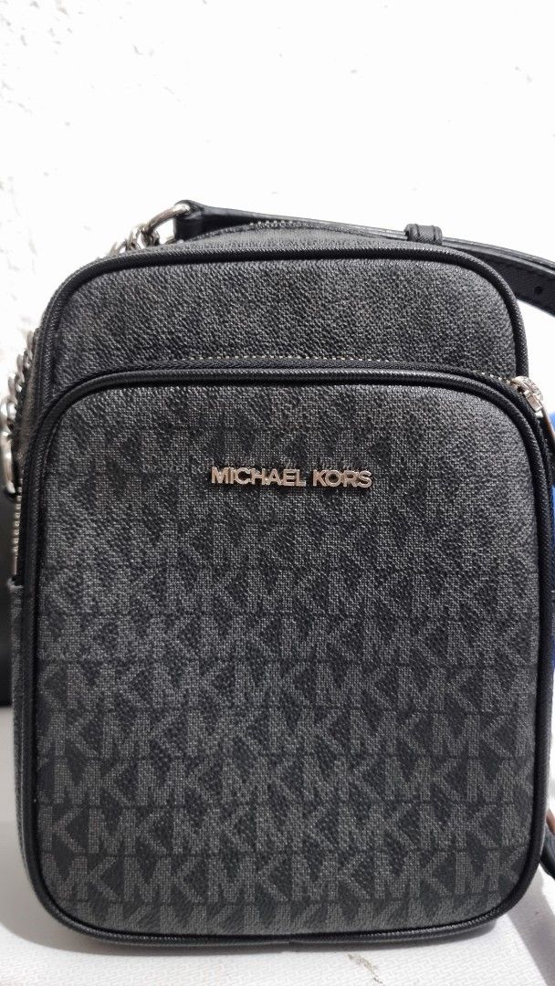 Michael Kors MK Monogram Black Crossbody Bag (Category: Luxury Bags & Wallets) located in Quezon City. Submitted by finds.in.closet (Listing ID 1471221835, Image 1). Description: - Brand: Michael Kors - Color: Black with signature MK monogram print - Compartments: Double zip top compartments plus an extra front pocket - Interior: Fabric lining with MK branding, very clean condition - Hardware: Silver-tone with chic chain strap detail on the side 