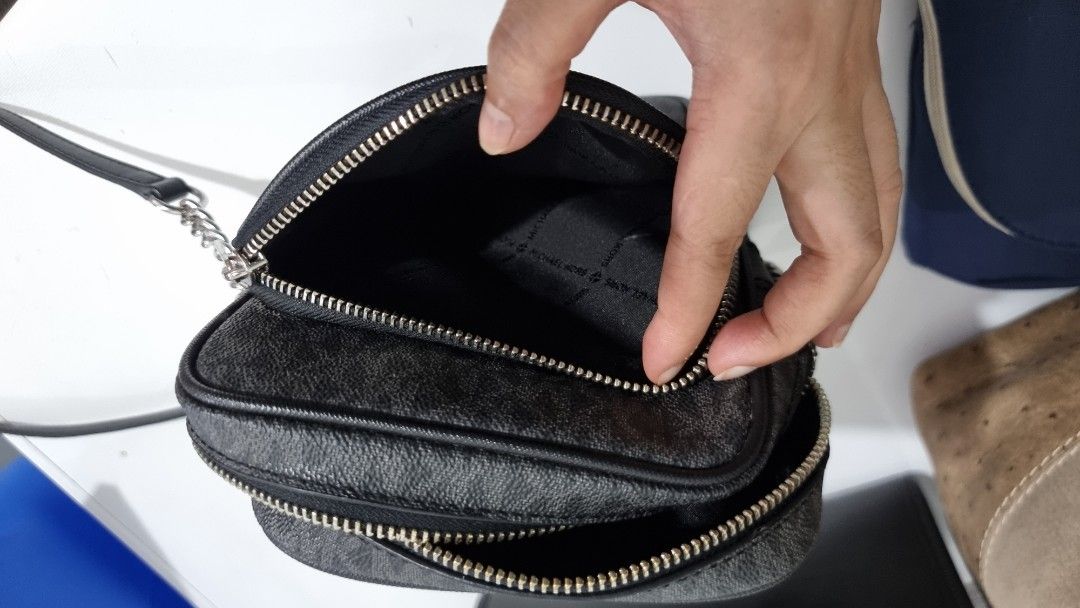 Michael Kors MK Monogram Black Crossbody Bag (Category: Luxury Bags & Wallets) located in Quezon City. Submitted by finds.in.closet (Listing ID 1471221835, Image 3). Description: - Brand: Michael Kors - Color: Black with signature MK monogram print - Compartments: Double zip top compartments plus an extra front pocket - Interior: Fabric lining with MK branding, very clean condition - Hardware: Silver-tone with chic chain strap detail on the side 