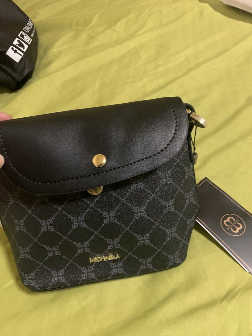 MICHAELA Black Monogram Pattern Crossbody Bag (Category: Cross-body Bags) located in Manila. Submitted by angelyrrehc (Listing ID 1471141658, Image 3). Description: - Brand: MICHAELA - Color: Classic black with all-over monogram pattern - Hardware: Elegant gold - Closure: Flap top with secure snap button - Interior: Brown fabric lining with an extra slip pocket -Size: 8.5x6.5x3.5inches - Strap: Adjustable shoulder strap (still wrapped in plastic)