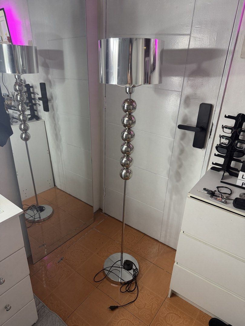 Modern Chrome Floor Lamp with Stacked Sphere Stem (Category: Lighting) located in Manila. Submitted by lexichiu77 (Listing ID 1471187070, Image 1). Description: - Height: Tall silver floor lamp with a clean, polished look - Shade: Stylish shiny metallic drum shade with a unique stacked chrome sphere detail on the stem - Stability: Heavy round metal base ensures it stays securely in place - Convenience: Standard plug with an easy-to-use inline foo