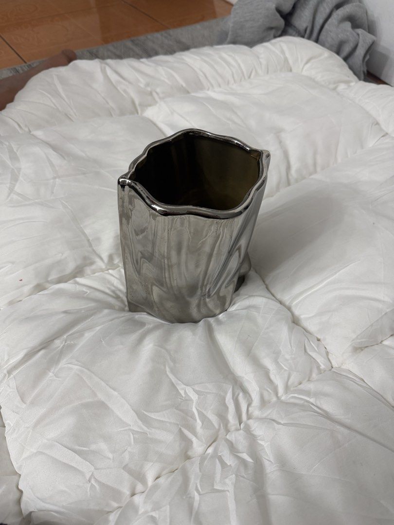 Modern Silver Metallic Ceramic Vase Home Decor (Category: Vases & Decorative Bowls) located in Manila. Submitted by lexichiu77 (Listing ID 1471216724, Image 3). Description: - Material: Ceramic with a smooth, glossy silver metallic finish - Design: Modern abstract shape with a unique organic, squished look - Versatility: Ideal for a small bouquet or as a standalone decor piece - Placement: Perfect for styling on shelves, coffee tables, or desks -