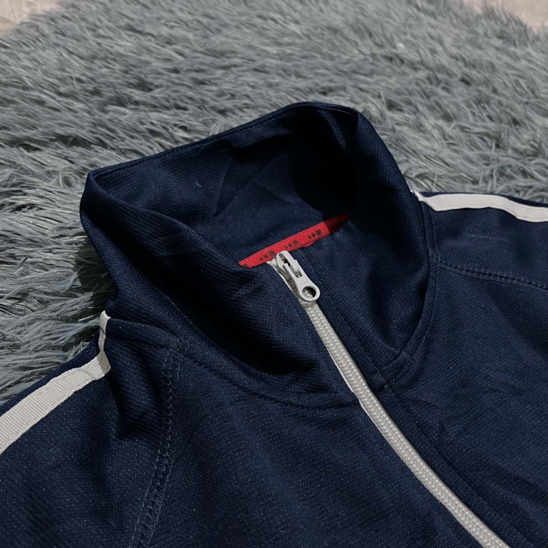 Navy Blue Track Jacket With White Stripes (Category: Coats, Jackets and Outerwear) located in Batangas. Submitted by jaylord_g (Listing ID 1471124163, Image 3). Description: - Color: Dark navy blue with contrasting white stripes and front piping - Fit & Style: Stand-up collar, full zip closure with silver pull, long sleeves with ribbed cuffs - Details: Small white graphic on lower back hem, interior red fabric detail with Japanese text tags - Mat