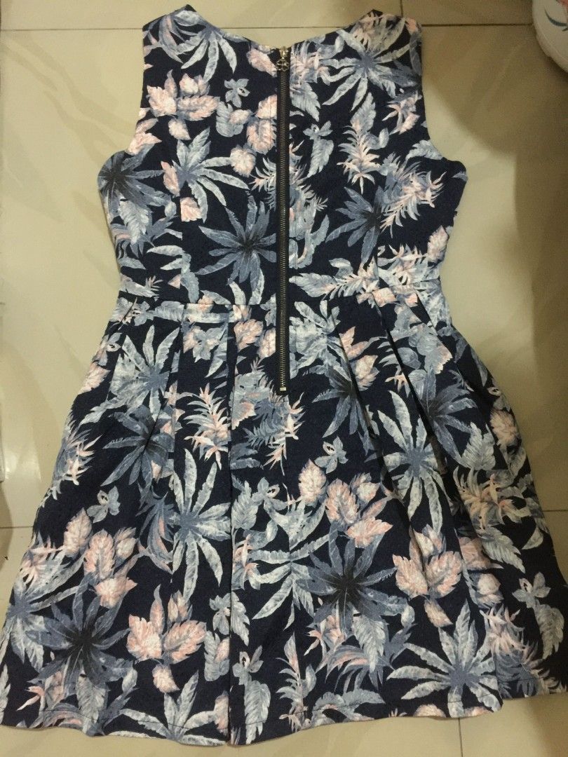 Navy Blue Tropical Leaf Print Dress (Category: Dresses) located in Marikina City. Submitted by sunflora.thrift (Listing ID 1471280350, Image 2). Description: - Brand/Label: Zhuangya Collection - Design: Navy blue with vibrant tropical leaf and floral print - Cut: Sleeveless, fitted bodice, and chic flared pleated skirt - Closure: Full-length metal zipper down the back - Material: Lightweight, breathable fabric ideal for warm weather and casual da