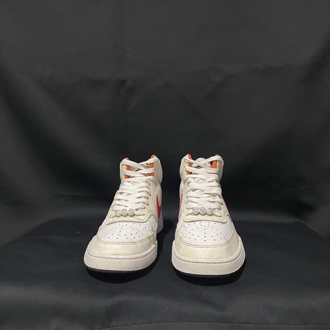 Nike Court Vision Mid White Red Orange (Category: Sneakers) located in Bulacan. Submitted by ogieeee (Listing ID 1471260152, Image 1). Description: - Brand: Nike - Style: Mid-top sneakers - Upper: White tumbled leather with red swoosh and orange collar accents - Soles: Textured rubber outsole with a speckled pattern (minimal wear) - Details: White laces with small bead charms near the toe box and embroidered Nike text on the heel - Condition: Cle