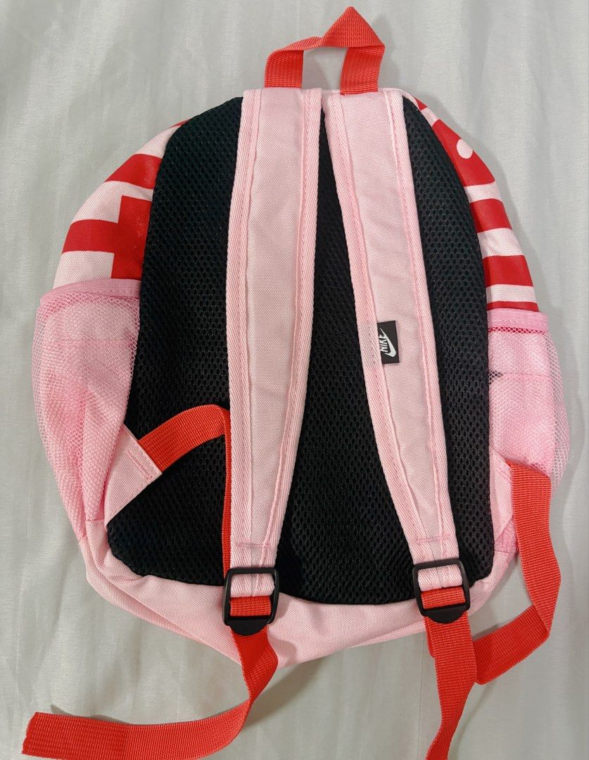 Nike Pink and Red Mini Backpack (Category: Backpacks) located in Manila. Submitted by jrpororo (Listing ID 1471233620, Image 2). Description: - Authentic Nike mini backpack in a vibrant pink and red colorway - Features a large Nike Swoosh logo on the front zipper pocket - Convenient mesh side pockets for water bottles - Comfortable black breathable mesh padding on the back panel - Adjustable red straps with durable black plastic buckles - Include