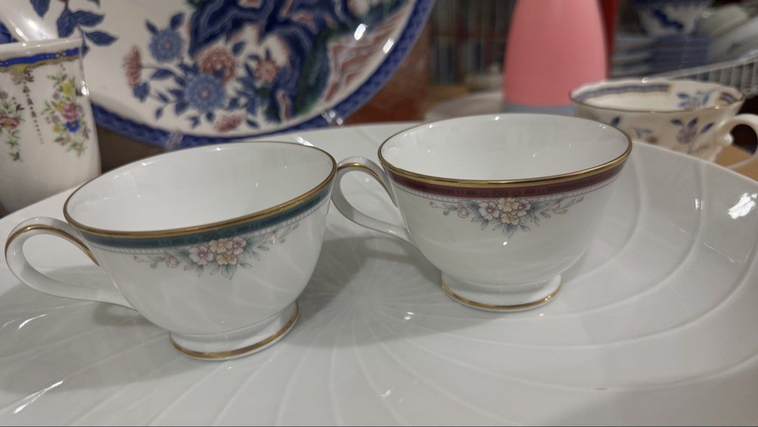 Noritake Klandon Fine Bone China Teacups (Category: Coffee & Tea Tableware) located in Masinloc. Submitted by kristineba02273 (Listing ID 1471157839, Image 2). Description: - Brand/Pattern: Noritake Klandon - Material: Fine bone china / white porcelain - Origin: Made in the Philippines - Quantity: Set of 2 teacups (one with a teal border, one with a burgundy band) - Design: Delicate pastel floral clusters and elegant gold trim on rims and footed 