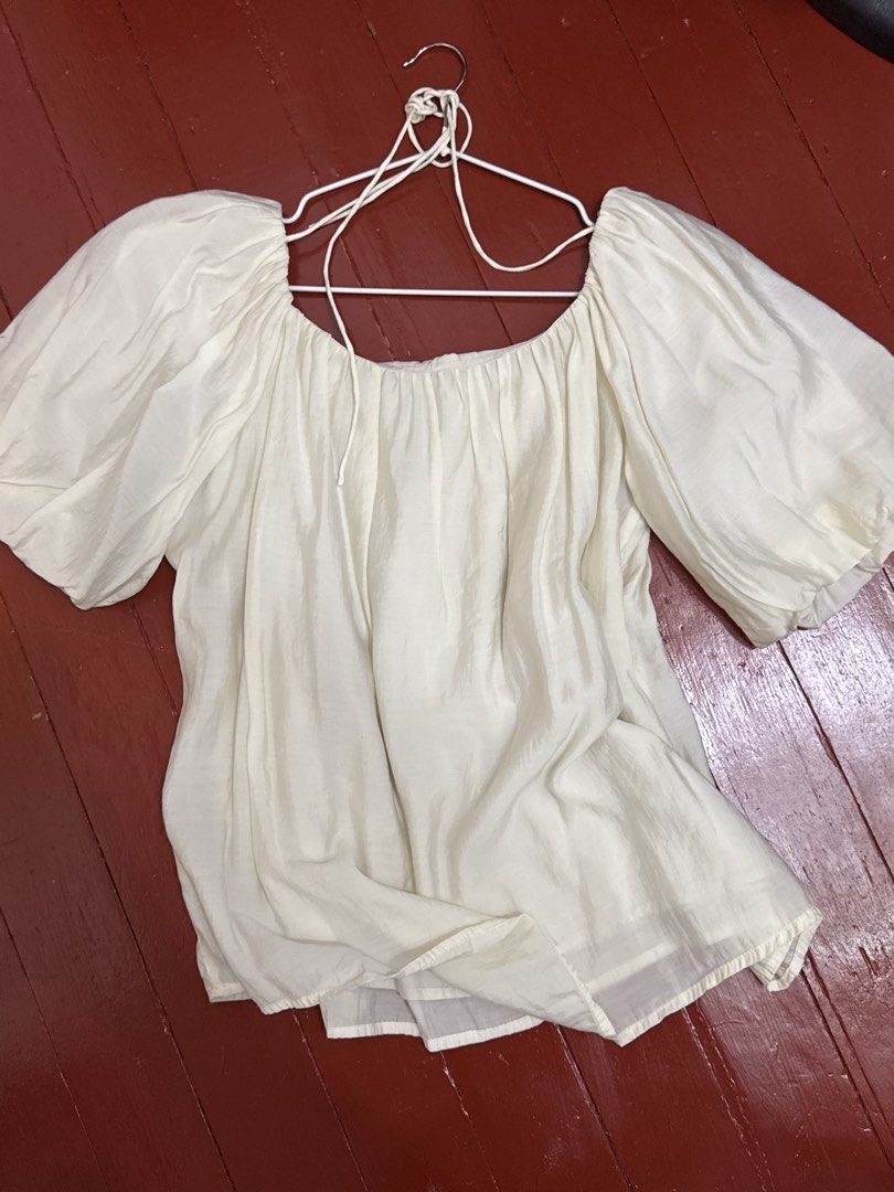 Off shoulder white puff sleeve blouse (Category: Blouses) located in Cavite. Submitted by luisascloset_ (Listing ID 1471216190, Image 2). Description: - Color: Off-white - Design: Off-shoulder with puffy half-sleeves - Details: Gathered neckline with adjustable front string ties - Fabric: Lightweight and flowy - Fit: Free size - Styling: Easy to pair with skirts or denim.