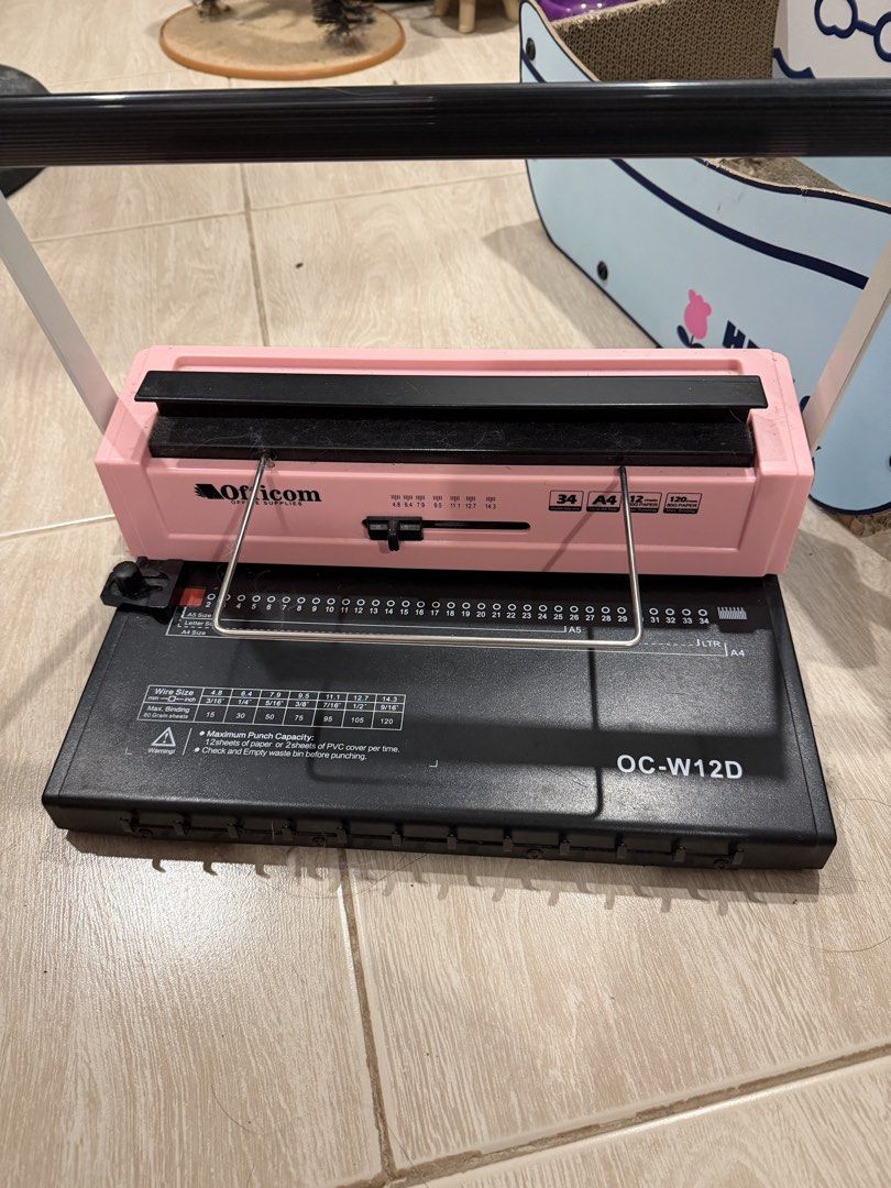 Officom OC-W12D Wire Binding Machine (Category: Office & Business Technology) located in Quezon City. Submitted by leilamiiii (Listing ID 1471209566, Image 1). Description: - Model: Officom OC-W12D (Pink and Black) - Paper Size: Handles up to A4 size - Punching Capacity: Punches up to 12 sheets at once - Features: Built-in wire size guide and clear alignment markings - Build: Sturdy metal handle across the top - Condition: Fully functional, perfe