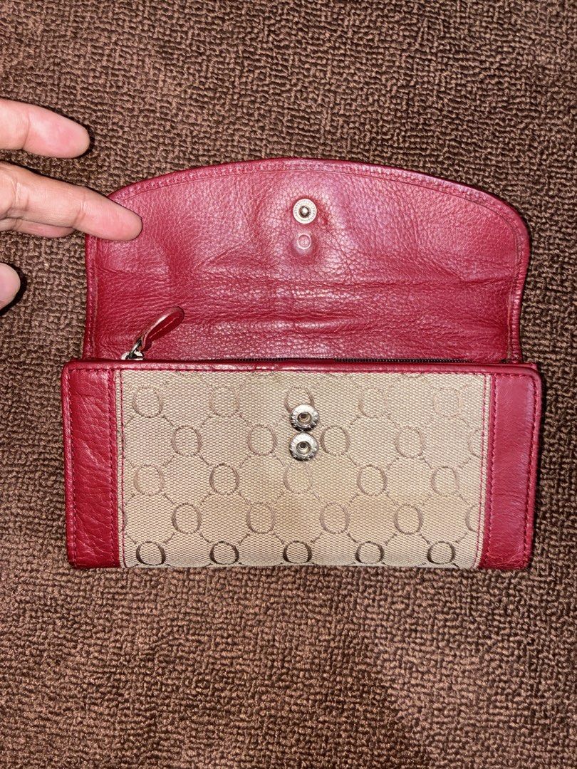 Oroton Red and Beige Monogram Long Wallet (Category: Wallets & Card holders) located in Placer. Submitted by talaalond61563 (Listing ID 1471226746, Image 2). Description: - Brand: Oroton - Material: Red leather and beige monogram fabric - Closure: Flap with silver-tone ring buckle and double snap buttons - Interior Features: Multiple card slots, ID window, and zippered compartment - Lining: Deep red grained leather throughout - Branding: Debossed