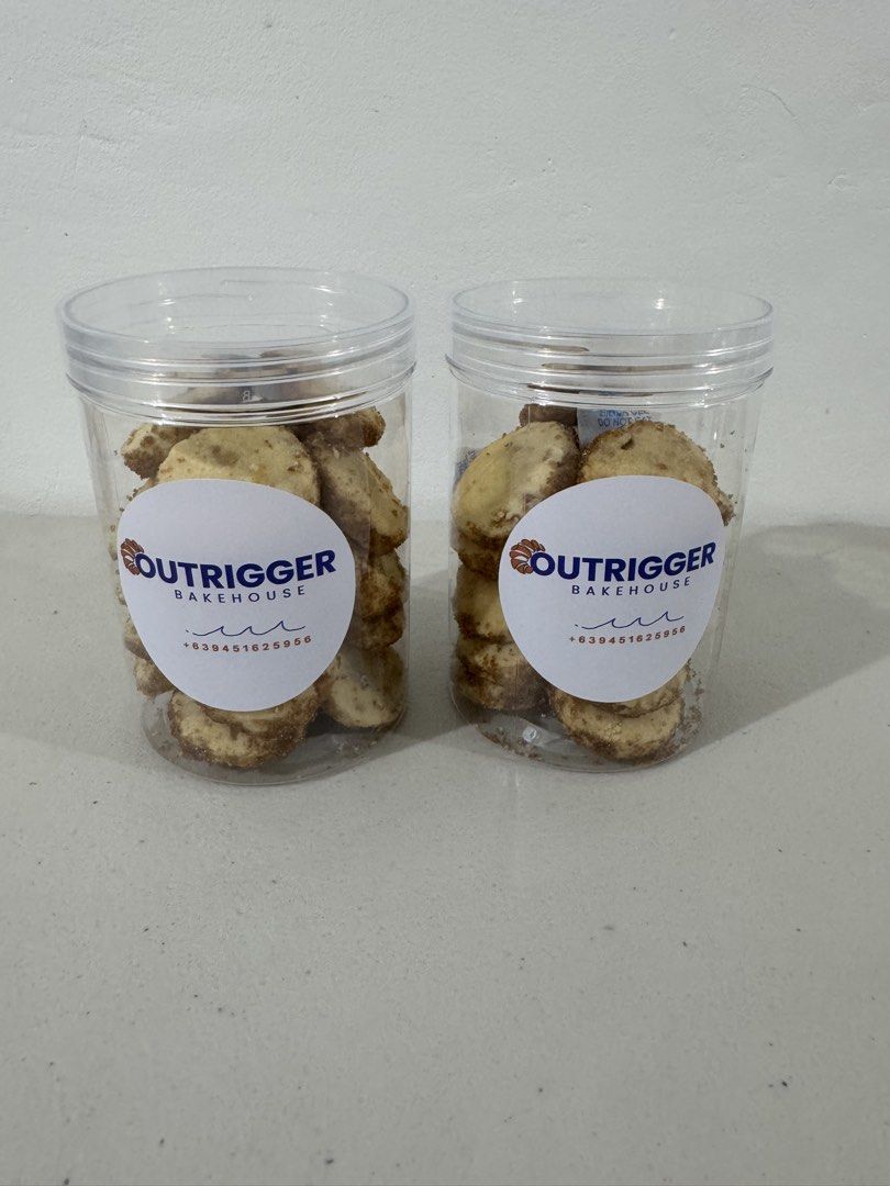 Outrigger Bakehouse cookies in jars and gift boxes (Category: Homemade Bakes) located in Quezon City. Submitted by itsublime (Listing ID 1471256708, Image 1). Description: - Freshly baked Outrigger Bakehouse cookies - Packed in clear plastic jars with custom labels (Contact: +639451625956) - Also available in tall green Christmas gift boxes with festive geometric patterns and red ribbons - Ideal for holiday gifting, parties, or personal snacking.