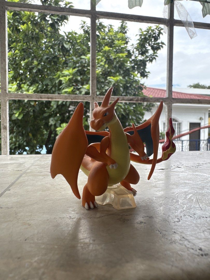 Pokemon Charizard Action Figure with Clear Base (Category: Figurines & Statues) located in Quezon City. Submitted by JDC_Onlineshop (Listing ID 1471145446, Image 1). Description: - Official Pokémon Charizard collectible figure - Vibrant orange body, cream belly, and dark blue wing interiors - Features detailed flame on the tail - Stands securely on a clear acrylic base - Clean piece with solid paint application - Perfect for collector shelves or 