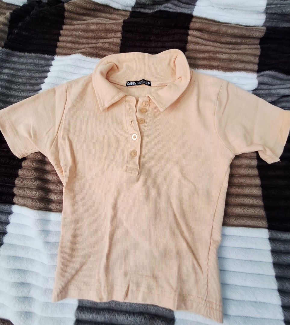 Polo shirts and Crop top (Category: Shirts) located in Angeles City. Submitted by cloudzies041456 (Listing ID 1471128694, Image 2). Description: Peach ribbed polo shirt from Zara. Short sleeves with a button placket at the neckline. Fitted cut through the body. Soft ribbed knit fabric with stretch. Neutral tone goes with everything. Easy to style with high-waisted jeans or skirts. Clean condition inside and out..