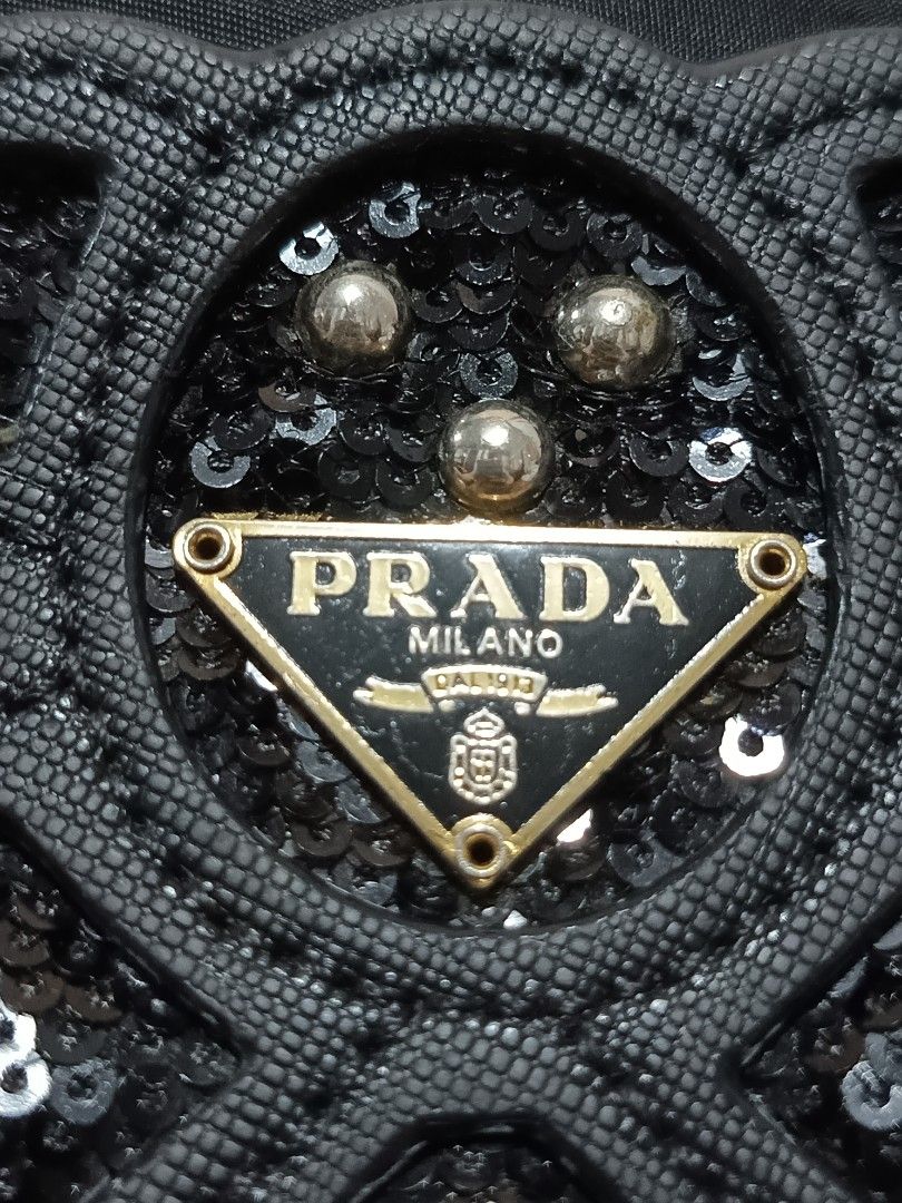 Prada Black Nylon Teddy Bear Sequin Crossbody Bag (Category: Luxury Bags & Wallets) located in Lucena. Submitted by jeankristi73450 (Listing ID 1471272303, Image 2). Description: - Prada black nylon crossbody bag - Features a sparkling sequin teddy bear design on the front - Elegant gold-tone chain strap intertwined with black fabric - Interior lined with signature Prada logo jacquard fabric - Convenient interior zipper pocket with branded pull t